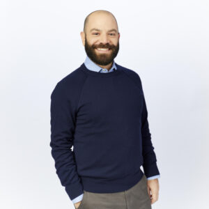 bearded, smiley white male in his 40s wearing a blue sweater.