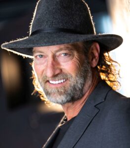 An image of actor Troy Kotsur, bearded white male, wearing a grey hat.