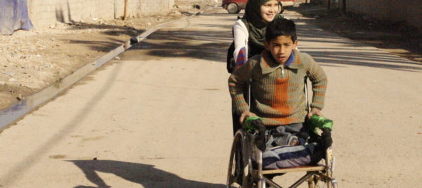 A person pushes a boy in a wheelchair
