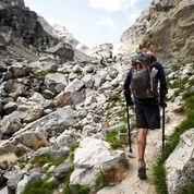 A man with a backpack hikes up a rocky trail