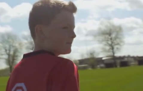 A boy in a red shirt stands in a field