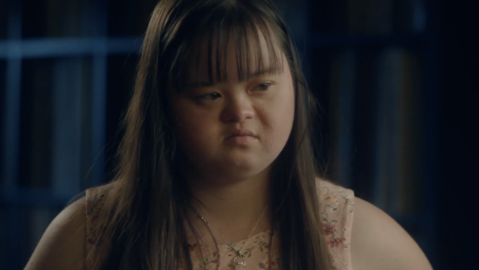 a young girl with Down syndrome looking sideway upset