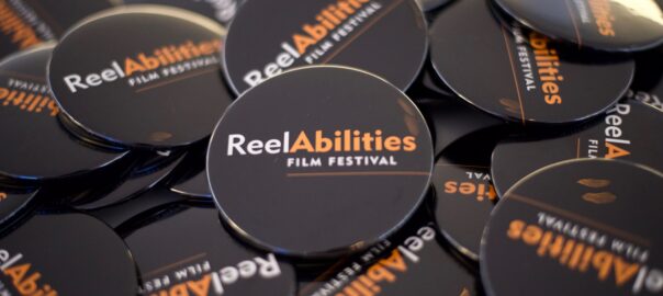 a pile of round dash pins with ReelAbilities Film Festival logo printed on.